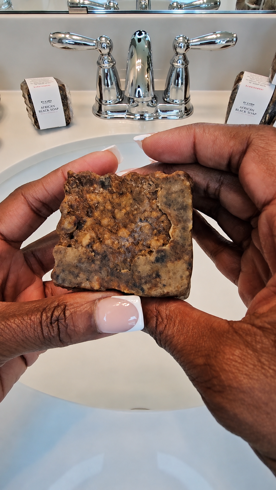 Natural handmade texture of by A’amia African Black Soap held over a bathroom sink before use.