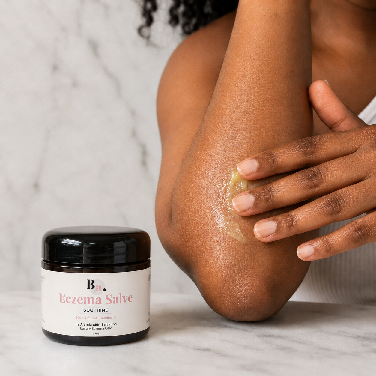 Black woman applying by A’amia Eczema Salve to her elbow for targeted richer care.